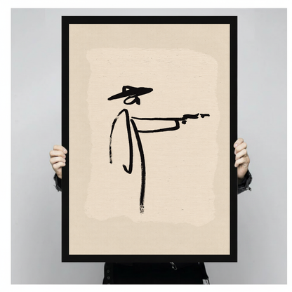 Person holding black framed minimalist brushstroke cowboy artwork against a plain pale background.