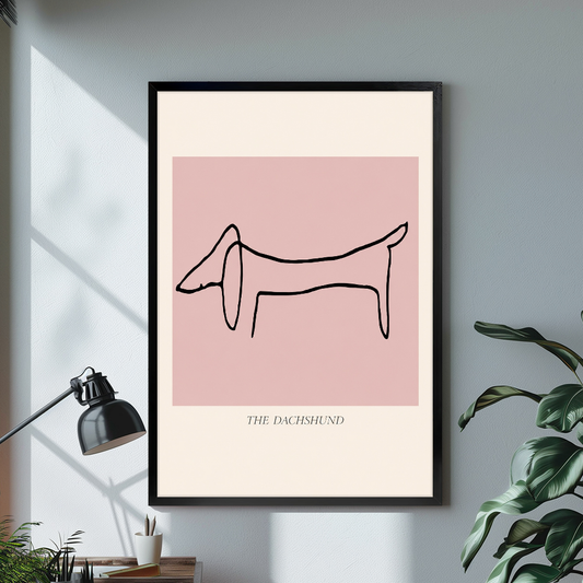Black framed minimal dachshund line drawing canvas on a pale wall above a desk and plant.