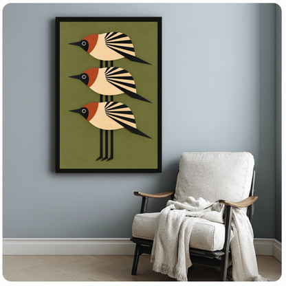 Framed three stacked folk birds canvas beside a pale reading chair on a blue gray wall.