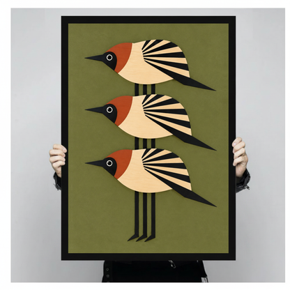 A person holds black framed three stacked folk birds canvas against a light neutral background.