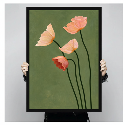 A person holds black framed four blush poppies canvas against a light neutral background.