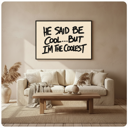 Framed he said be cool quote canvas above a beige sofa beside pampas grass and a wooden table.