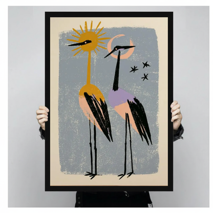 Framed sun moon crane companions canvas held by a person against a light neutral background.