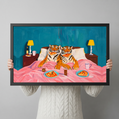 Framed tigers enjoy pizza in bed canvas held horizontally by a person wearing a cream sweater against a light background.