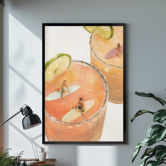 Black framed tiny surfers cocktail pools canvas on a pale wall above a desk and plant.