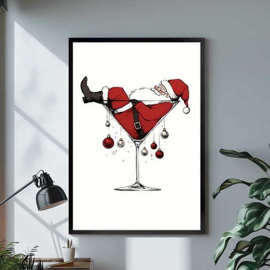 Black framed santa in martini glass canvas on a pale wall above a desk and plant.