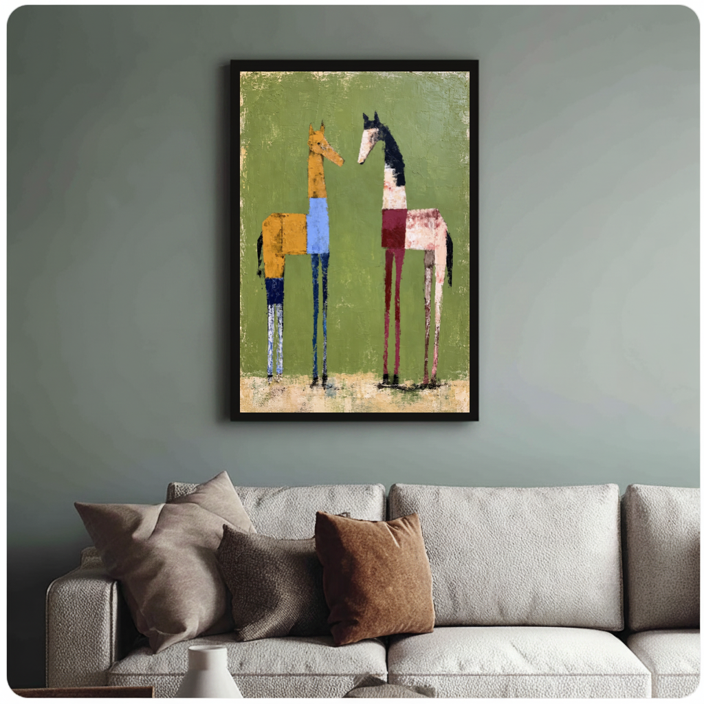 Framed two green field horses canvas above a neutral sofa with cushions against a muted wall.