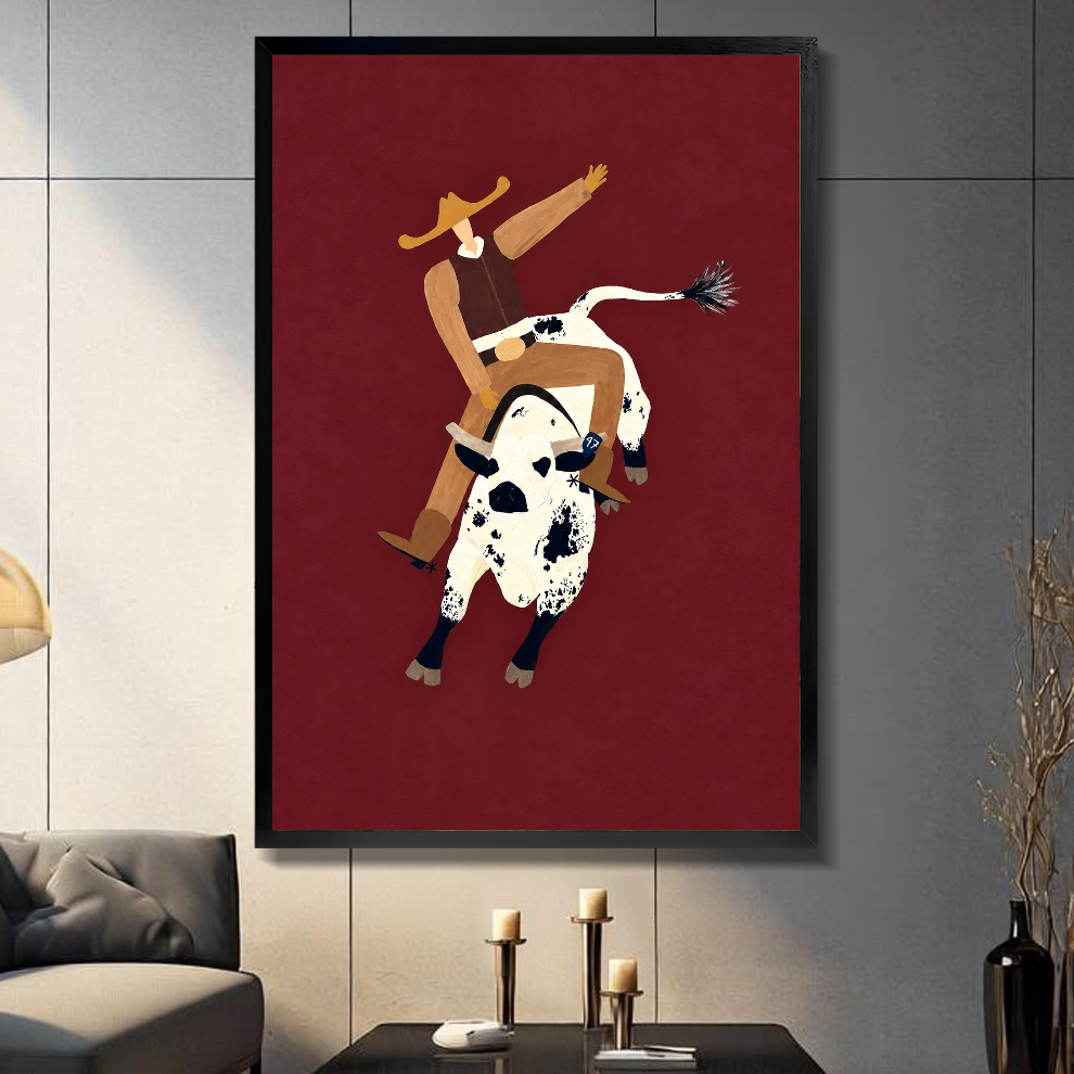 Black framed burgundy rodeo rider canvas on a dark paneled wall beside warm candles.