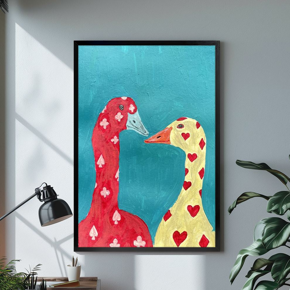 Black framed playing card geese canvas on a pale wall above a desk and plant.