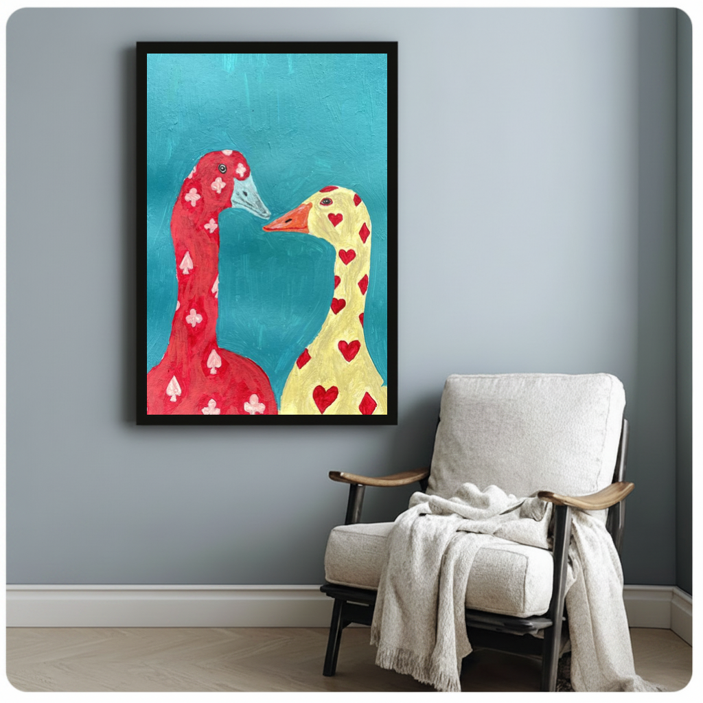 Framed playing card geese canvas beside a pale reading chair on a blue gray wall.