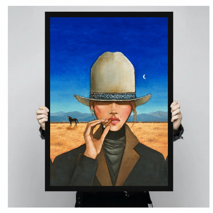 Framed blue sky cigar cowgirl canvas held by a person against a light neutral background.