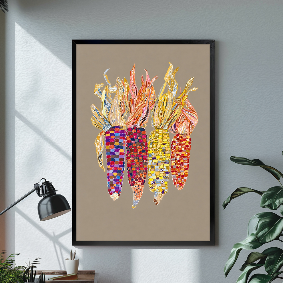 Black framed colorful beaded corn canvas on a pale wall above a desk and plant.
