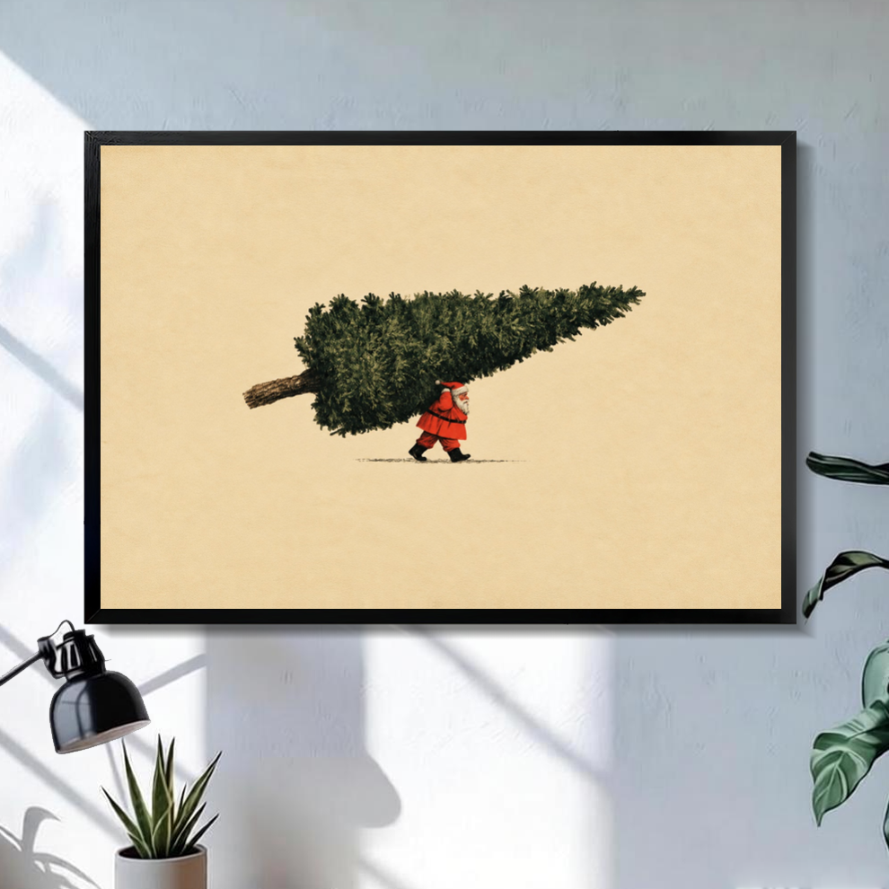 Black framed santa carrying christmas tree canvas on a pale wall above a desk and plant.