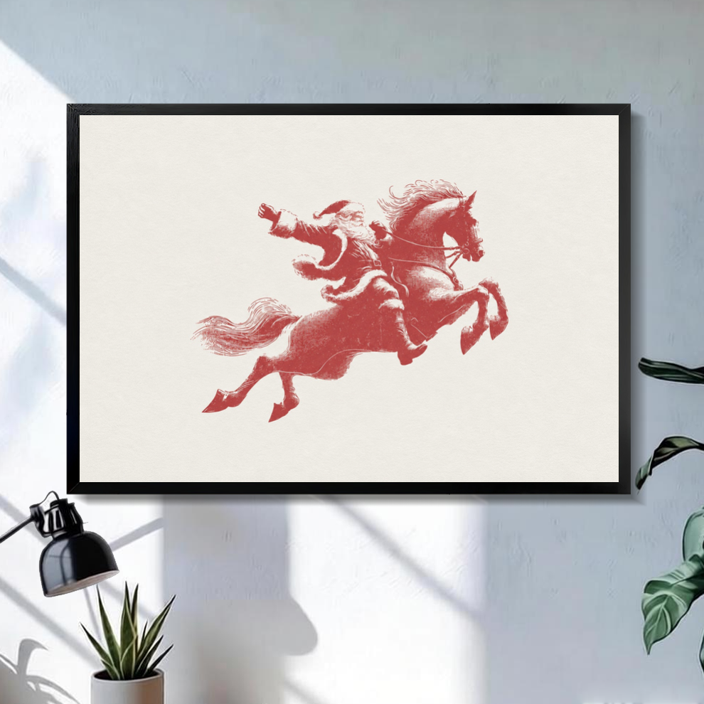 Black framed santa on red horse canvas on a pale wall above a desk and plant.