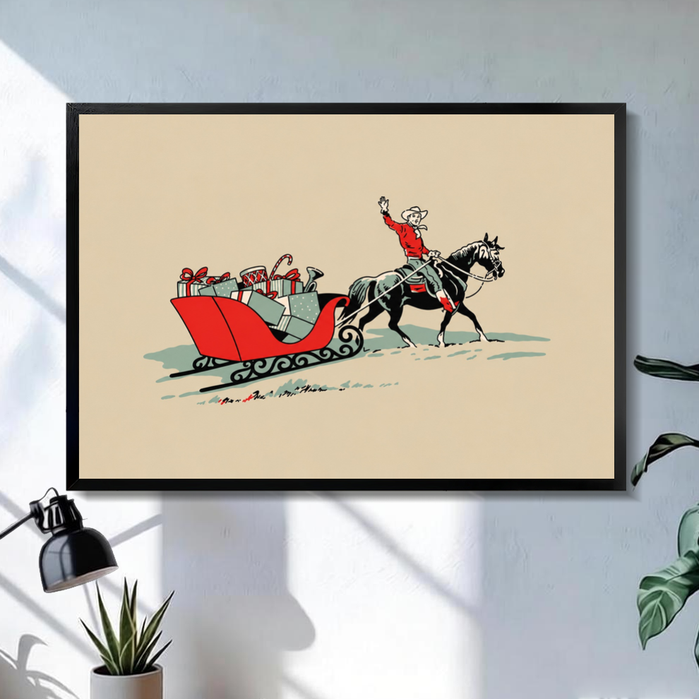 Black framed christmas cowboy gift sleigh canvas on a pale wall above a desk and plant.