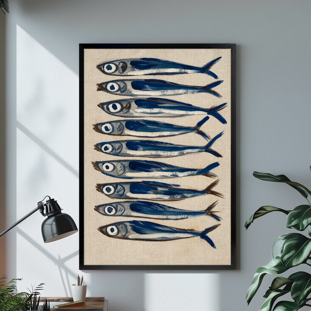 Black framed nine blue sardines canvas on a pale wall above a desk and plant.