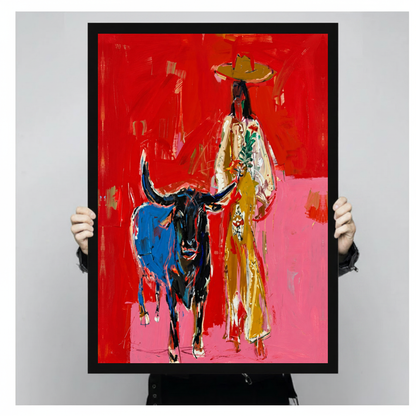 Framed red cowboy and bull canvas held by a person against a light neutral background.