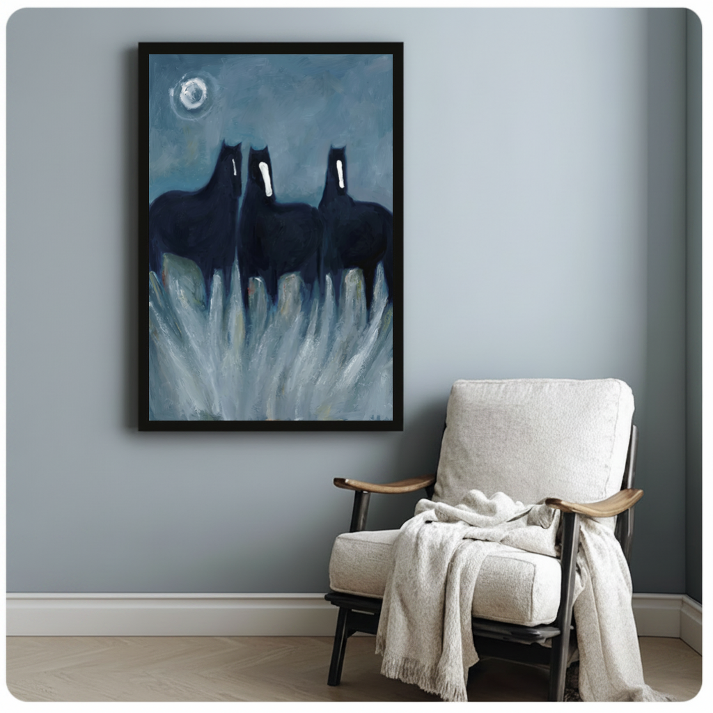 Framed three ghostly black horses canvas beside a pale reading chair on a blue gray wall.