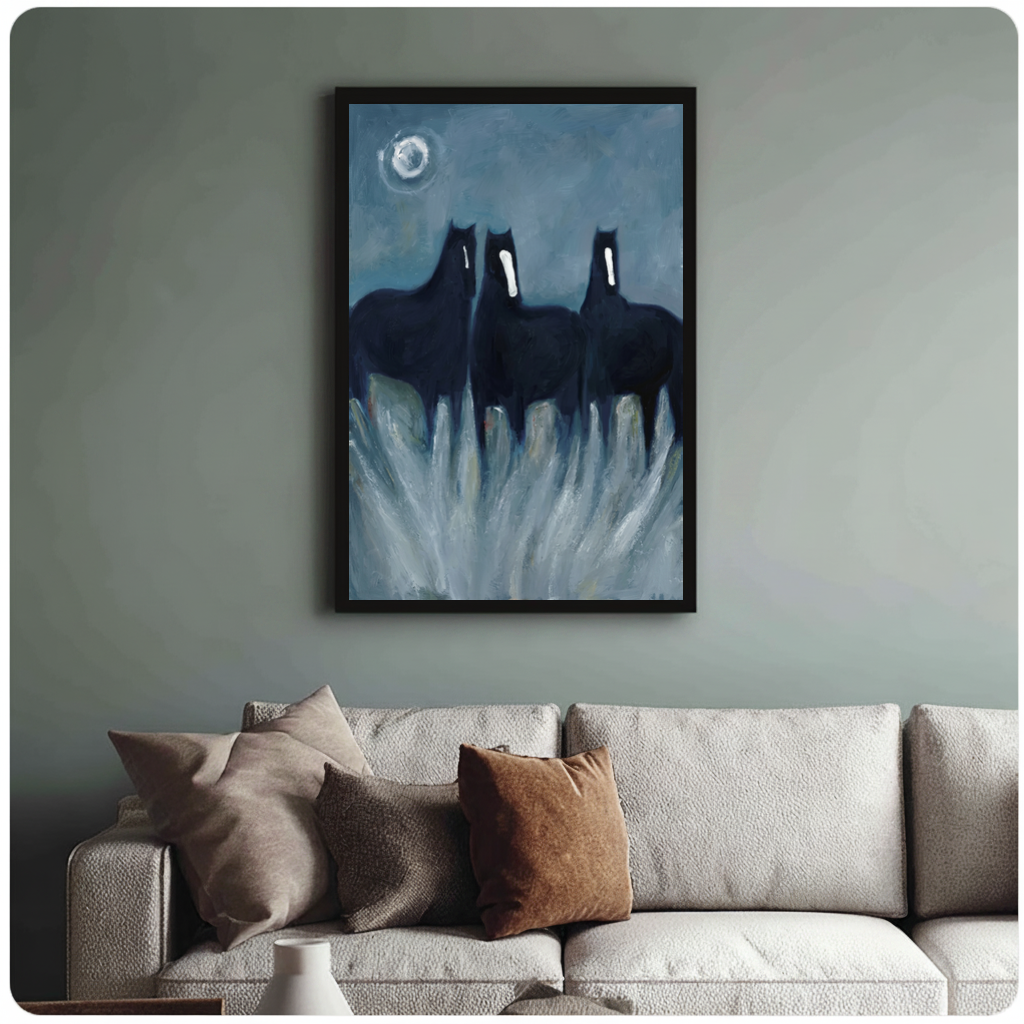 Framed three ghostly black horses canvas above a neutral sofa with cushions against a muted wall.