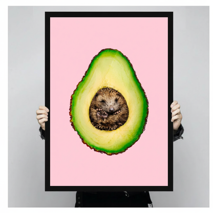 Framed avocado hedgehog canvas held by a person against a light neutral background.