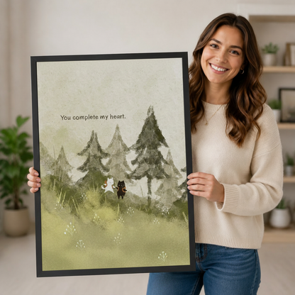 Person holding a large vertical black framed watercolor you complete my heart cat and dog canvas art print showing a white cat and black dog standing together in a misty pine forest meadow with the hand-lettered quote in soft sage green and gray watercolor tones in a bright plant-filled room
