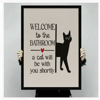 Hands holding large framed Welcome to the Bathroom black cat canvas print - full artwork detail of humorous cat typography with bold serif font red heart and black cat silhouette on cream background