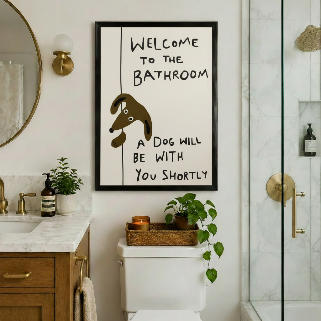 Funny dog bathroom poster framed in black hung above toilet in a warm-toned bathroom with marble countertop gold fixtures and green plants