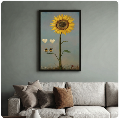 Whimsical framed poster of two bees perched on a sunflower stem with floating heart balloons, hung above a neutral linen sofa