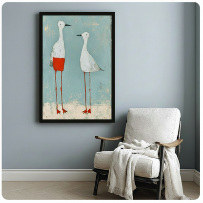 Black framed folk art print featuring two long-legged white birds on a distressed teal background, styled beside a linen accent chair