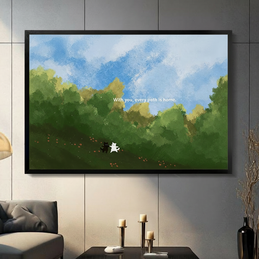Whimsical black and white cat duo "With you every path is home" black framed canvas art in lush green landscape above a dark console table with candle holders in a modern living room