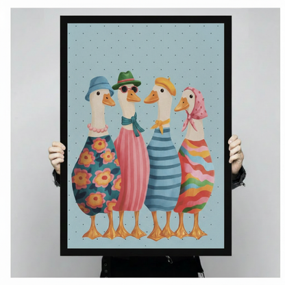 Hands holding a large black framed whimsical fashionable ducks squad canvas art print with four stylish white ducks in colorful hats and patterned outfits on a soft blue polka dot background