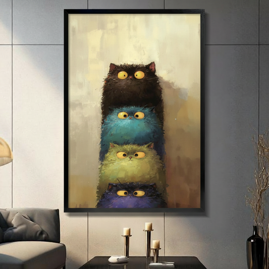 Black framed whimsical stacked fluffy cats with big yellow eyes canvas art with four round chubby cats piled vertically from top to bottom in dark brown teal yellow-green and deep purple with wide startled yellow eyes and shaggy textured fur in moody oil-paint style against a warm golden amber brushstroke background, hung on a gray panel wall above a dark gray sofa