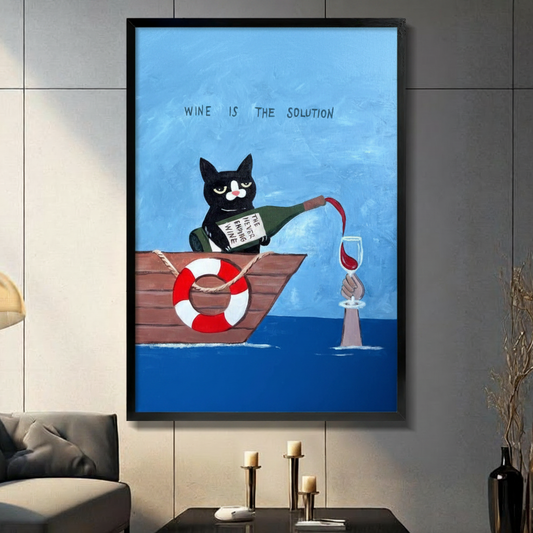 Black framed whimsical wine is the solution tuxedo cat in a boat canvas art with a black and white cat pouring red wine from a never ending wine bottle into a glass held by a hand rising from the sea, a red and white life ring on the wooden boat, and hand-lettered text on a blue oil-painted background, displayed on a dark gray tile wall above a black table with candlesticks beside a gray sofa