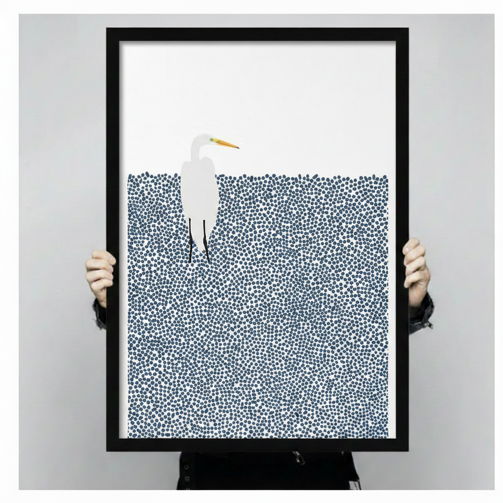 Person holding a large black framed minimalist white egret in pointillist navy blue water art print showing print size scale and fine dot texture detail