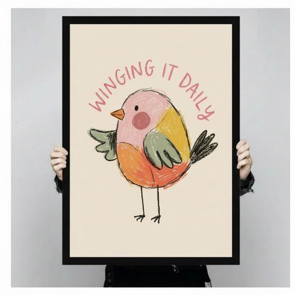 Close-up of Winging It Daily chubby bird poster held by hands showing crayon illustration detail and pink text