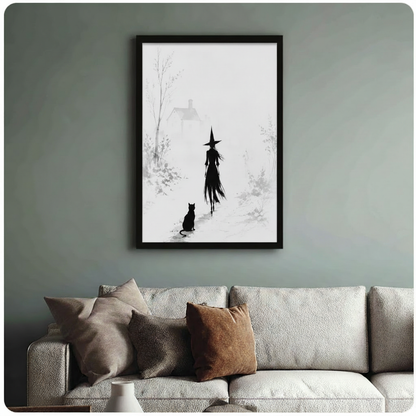 Black framed canvas art of a witch and black cat silhouette on a misty path toward a cottage, hung above a neutral linen sofa on a sage green wall