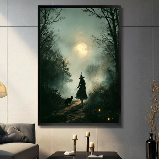 Gothic romantic oil painting of a mysterious witch silhouette in a layered dark dress and tall pointed hat walking a misty moonlit forest path accompanied by a black cat beside her holding a staff while a large glowing full moon breaks through the canopy of dark bare tree branches above with golden firefly lights scattered along the forest floor deep emerald green tones with ethereal blue-green mist witchcore dark cottagecore forest wall art framed print displayed in a living room with dark gray sofa, pilla