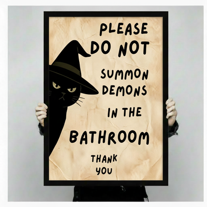 Two hands in black sleeves holding a large black framed whimsical bathroom humor canvas print of a black cat in a pointed witch hat peeking from the left edge with bold black hand-lettered typography Please Do Not Summon Demons in the Bathroom Thank You on a warm crinkled parchment background funny witch cat canvas art print, front-facing vertical product size display
