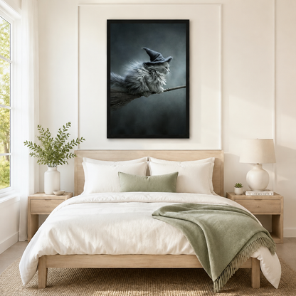 Moody gothic framed wall art of a majestic fluffy cat wearing a witch hat riding a broomstick through misty air, displayed above a neutral linen bed in a serene Scandinavian bedroom