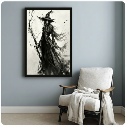 Dark gothic ink wash illustration of a witch standing upright in a billowing black dress beneath a wide-brimmed peaked hat her dark hair streaming in the wind as she rests beside a twisted dead tree with intricate bare branches and ink spatter with subtle bat silhouettes visible in the swirling skirt against an open white background with soft gray ink wash accents elegant gothic witch wall art framed print beside a white linen armchair on a blue gray wall