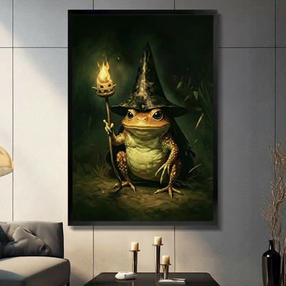 Black framed whimsical fantasy oil painting of a plump golden-brown toad wearing a wide-brim black wizard hat and dark cloak sitting upright and holding a thin branch staff topped with a bright orange flame in its right hand with intense forward-gazing eyes deep dark green forest background with warm golden light glow wizard toad canvas wall art displayed in a modern gray marble paneled living room with charcoal sofa black coffee table and three white pillar candles