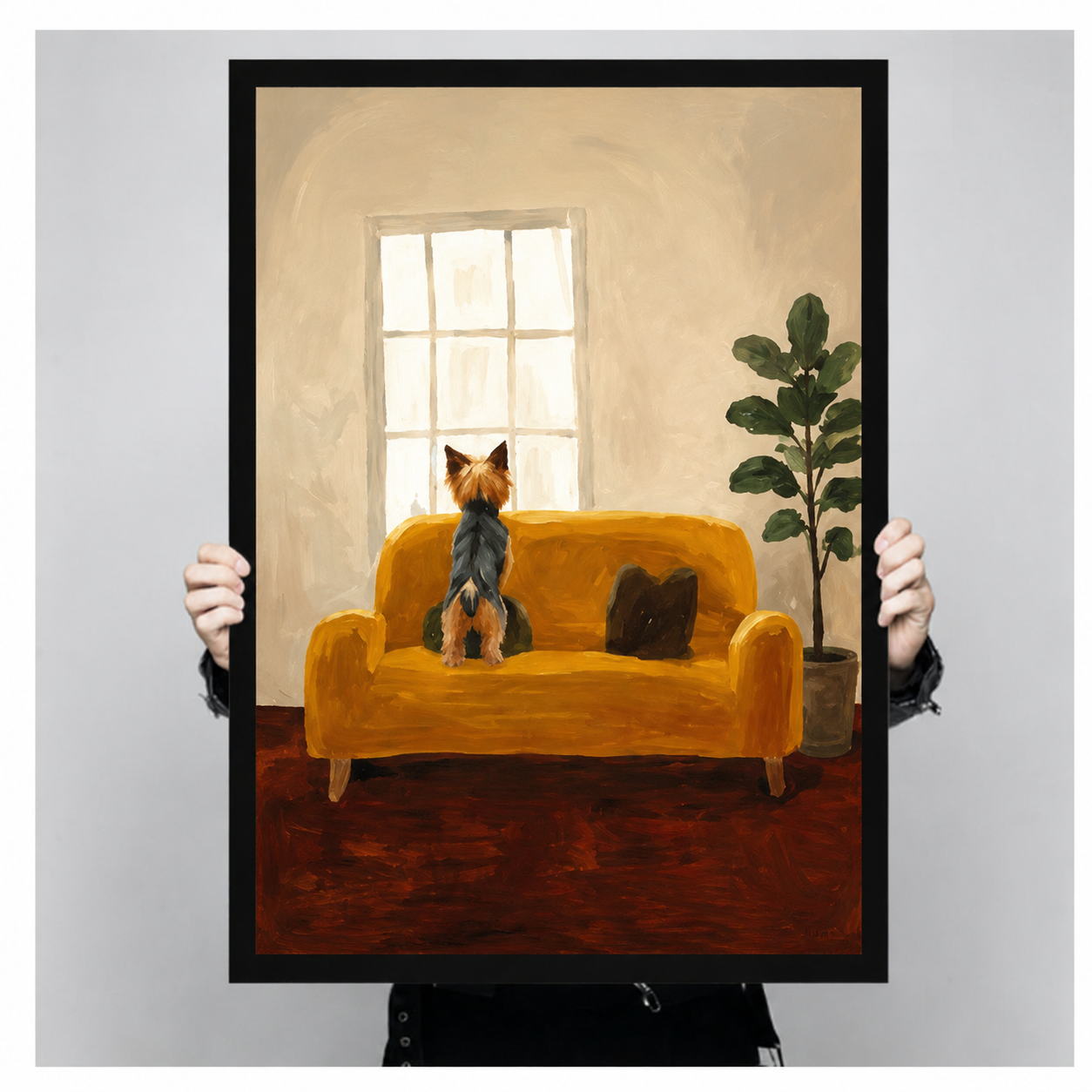 Hand-held black framed poster print of Yorkshire Terrier on mustard yellow sofa gazing out window in warm oil painting style