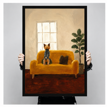 Hand-held black framed poster print of Yorkshire Terrier on mustard yellow sofa gazing out window in warm oil painting style