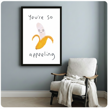 "You're So Appealing" funny banana pun framed wall art print displayed on grey-blue wall above armchair in cozy living room