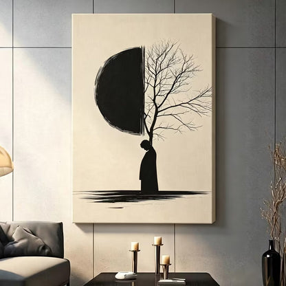 Contemporary zen ink art solitary figure silhouette with half black moon and bare winter tree branches gallery wrap canvas art on warm beige background on a dark gray paneled wall above a charcoal sofa with candle holders and a black vase
