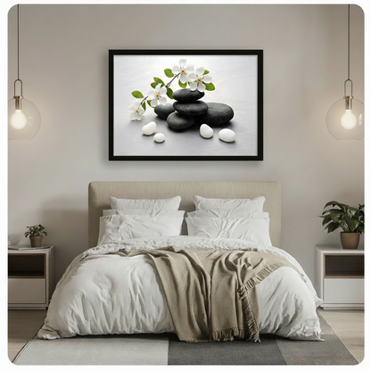 Black framed zen stones and white blossom branch canvas wall art above a beige upholstered headboard with white linen bedding, a taupe throw blanket, white nightstands, potted plants, and globe pendant lights