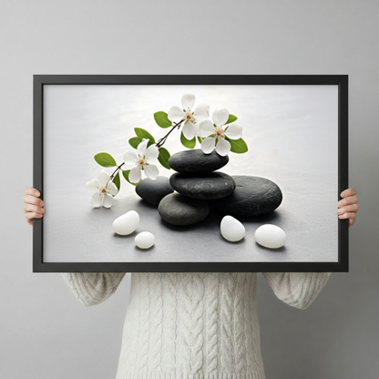 Person holding a black framed zen stones and cherry blossom canvas art print against a light gray backdrop showcasing print size and frame detail